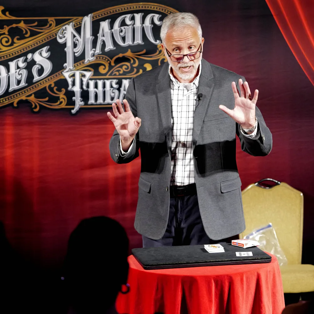 Mike Stringer on stage with hands raised behind a red performing table